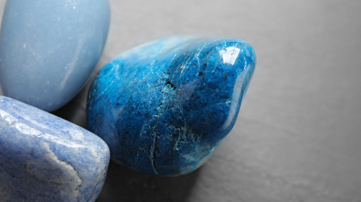 une belle pierre roulée de quartz bleu, entourée de pierre roulée de calcédoine