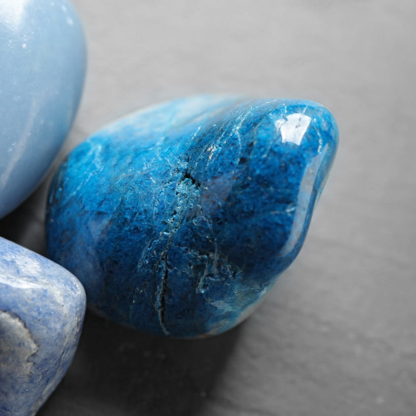 une belle pierre roulée de quartz bleu, entourée de pierre roulée de calcédoine