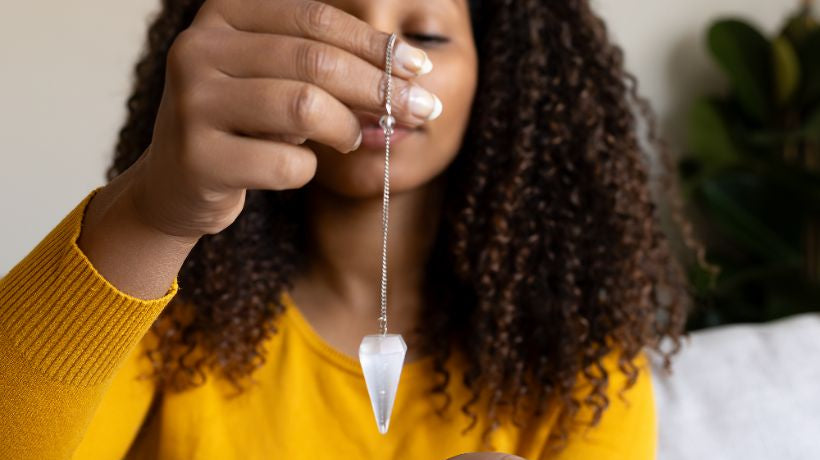 femme avec pendule en pierre naturelle radiesthesie
