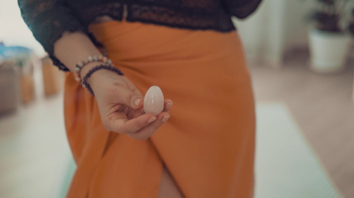 femme tiens un oeuf de yoni en quartz rose devant son perinee