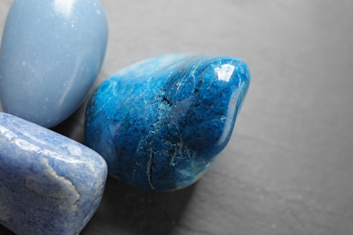 une belle pierre roulée de quartz bleu, entourée de pierre roulée de calcédoine