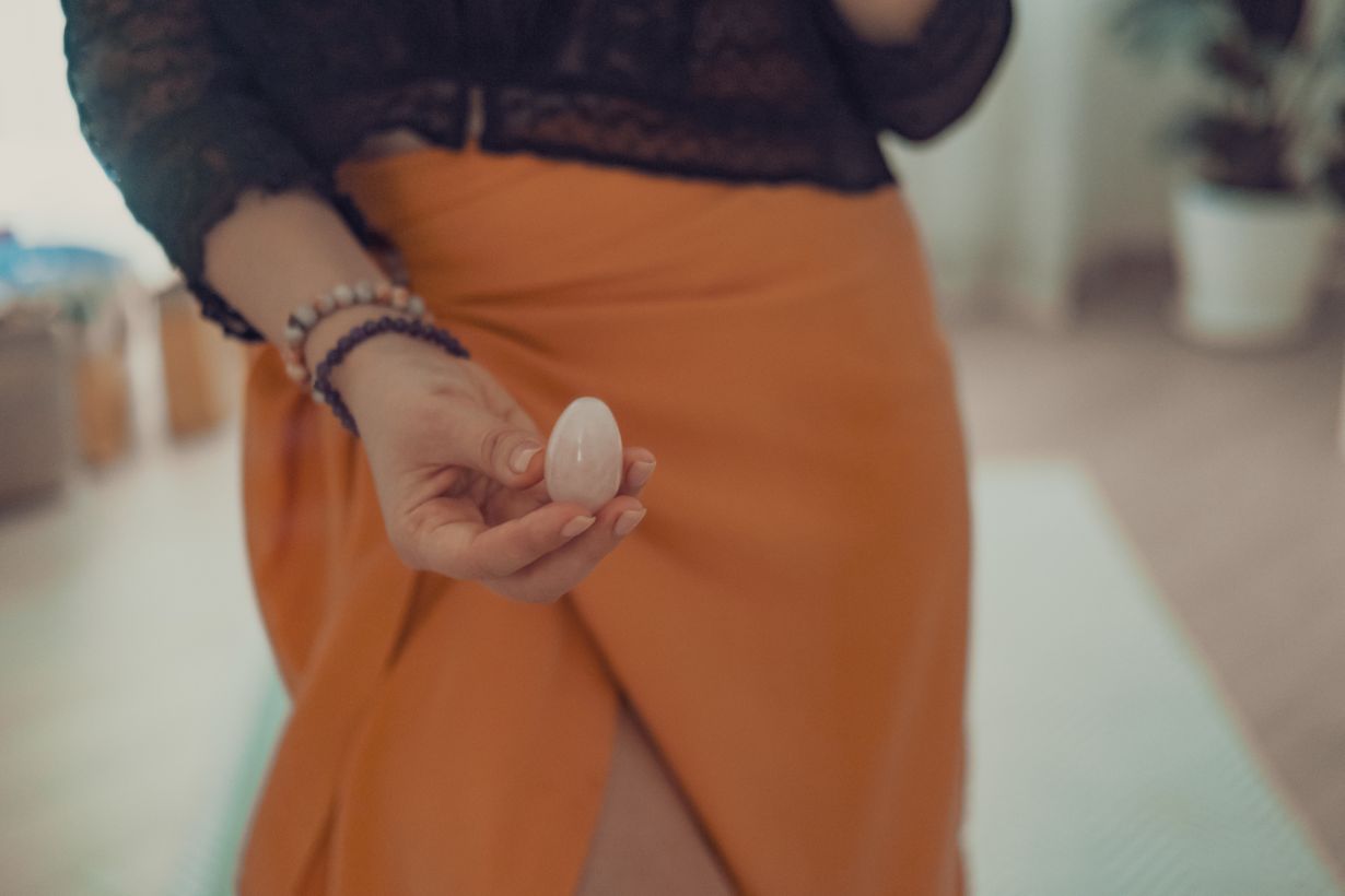 femme tiens un oeuf de yoni en quartz rose devant son perinee